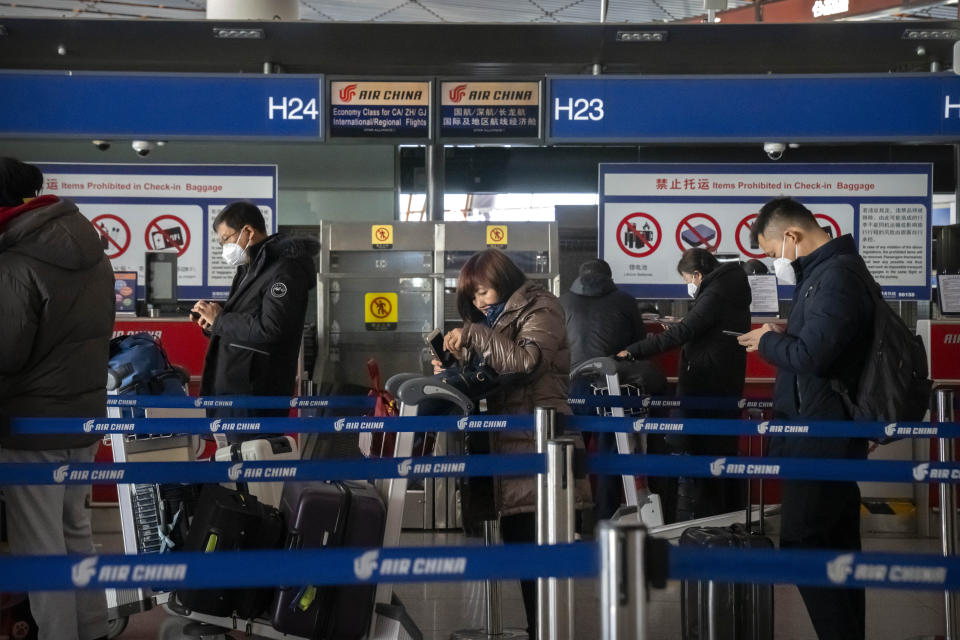Travelers stand in line at the Air China international flight check-in counter at Beijing Capital International Airport in Beijing, on Jan. 15, 2023. (AP Photo/Mark Schiefelbein)
