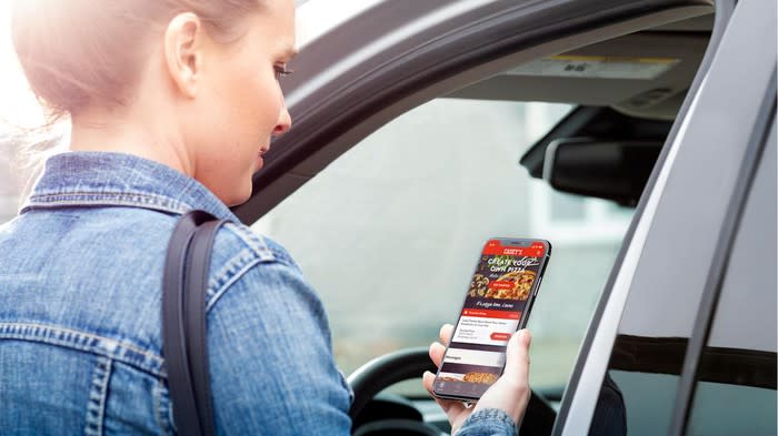 A customer with the Casey's mobile app contemplating a pizza order as she gets to her car.