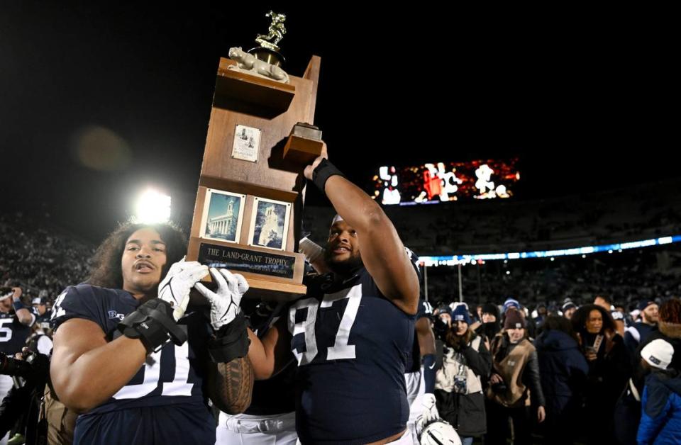 Penn State seniors Dvon Ellies and PJ Mustipher carry the Land-Grant Trophy after the win over Michigan State on Saturday, Nov. 26, 2022.