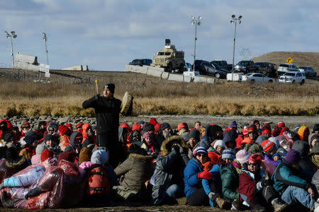 A man bangs a drum while police stand guard during a protest against plans to pass the Dakota Access pipeline near the Standing Rock Indian Reservation, near Cannon Ball, North Dakota, U.S. November 18, 2016. REUTERS/Stephanie Keith