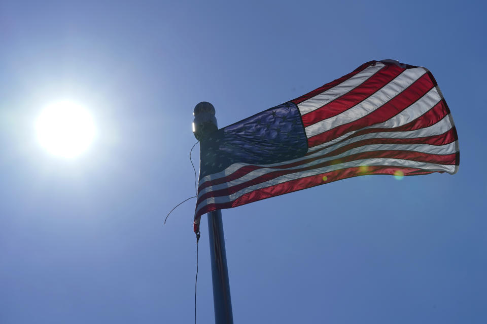 FILE - In this Wednesday, June 30, 2021 file photo, a U.S. flag flies with the sun in the background in downtown Seattle. According to a study released on Wednesday, July 7, 2021, the deadly heat wave that roasted the Pacific Northwest and western Canada “was virtually impossible without human-caused climate change” which also added a few extra degrees to the record-smashing warmth. (AP Photo/Ted S. Warren, File)