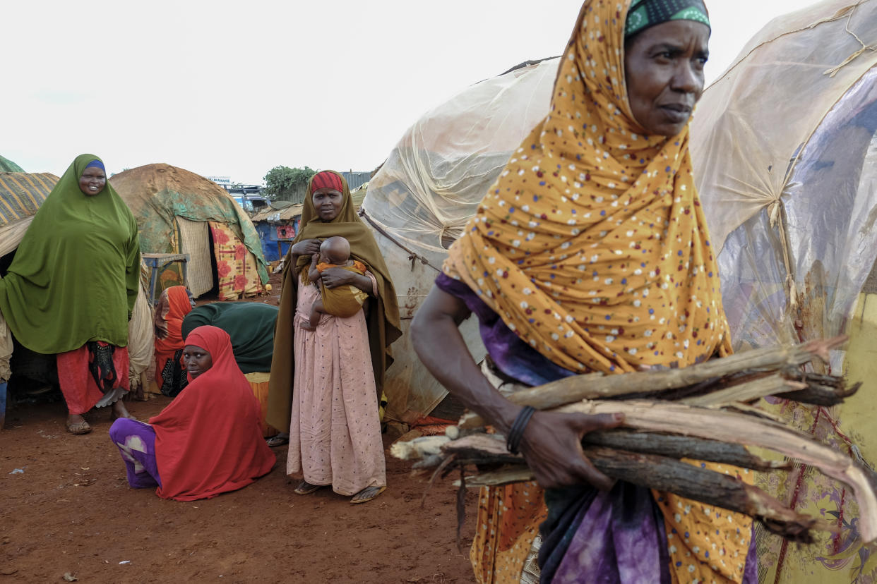 Nurto Hassan, right, carries firewood to cook for her children, as other women displaced by the drought look on, at a camp for the displaced on the outskirts of Baidoa, in Somalia Saturday, Oct. 29, 2022. Ships loaded with grain departed Ukraine on Tuesday, Nov. 1, 2022 despite Russia suspending its participation in a U.N.-brokered deal that ensures safe wartime passage of critical food supplies meant for parts of the world struggling with hunger such as Somalia. (AP Photo/Mohamed Sheikh Nor)