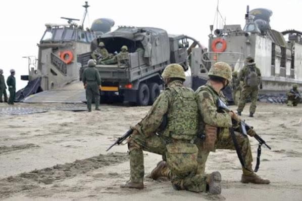 日本陸上自衛隊水陸機動團氣墊船搶灘，卸下軍用車輛等裝備，陸自水陸機動團士官兵在旁持槍戒備。日本統合幕僚監部