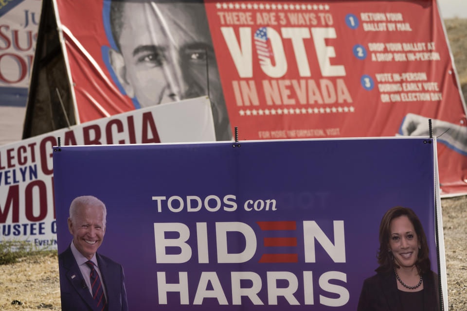 FILE - In this Nov. 6, 2020, file photo, a campaign sign supporting Democratic presidential candidate former Vice President Joe Biden and running mate Kamala Harris stands in front of a vote sign showing former President Barack Obama near the Clark County Election Department in North Las Vegas, Nev. A tough road lies ahead for Biden who will need to chart a path forward to unite a bitterly divided nation and address America’s fraught history of racism that manifested this year through the convergence of three national crises. (AP Photo/Jae C. Hong, File)