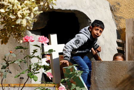 Children from families who fled their homes in Arish play next to a cross outside a rented apartment on the edge of Suez Canal in Ismailia, Egypt, April 24, 2017. Picture taken April 24, 2017. REUTERS/Mohamed Abd El Ghany