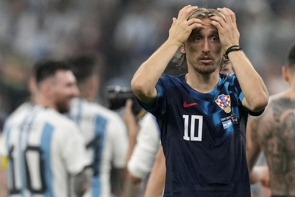 Croatia's Luka Modric reacts, while Argentina's Lionel Messi, background left, celebrates, at the end of the World Cup semifinal soccer match between Argentina and Croatia at the Lusail Stadium in Lusail, Qatar, Tuesday, Dec. 13, 2022. Argentina won 3-0. (AP Photo/Frank Augstein)