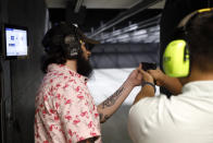 Firearms trainer Kevin Burke, left, instructs new gun owner Troy Deguzman during a shooting session at Maxon Shooter's Supplies and Indoor Range, Friday, April 30, 2021, in Des Plaines, Ill. After a year of pandemic lockdowns, mass shootings are back, but the guns never went away. As the U.S. inches toward a post-pandemic future, guns are arguably more present in the American psyche and more deeply embedded in American discourse than ever before. The past year's anxiety and loss fueled a rise in gun ownership across political and socio-economic lines. (AP Photo/Shafkat Anowar)