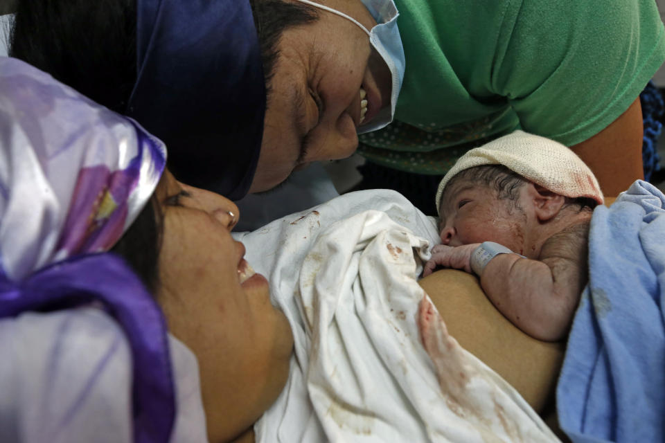 Angela Quintana Aucapan and her partner Cristian Fernandez Ancapan look at their newborn son, whom they named Namunkura, at the San Jose de Osorno Base Hospital in Osorno, Chile, Saturday, Aug. 20, 2022. Namunkura was born in a special delivery room with Native images on the walls and bed, an effort by the hospital to validate the cultural practices of Chile’s Indigenous groups. (AP Photo/Luis Hidalgo)