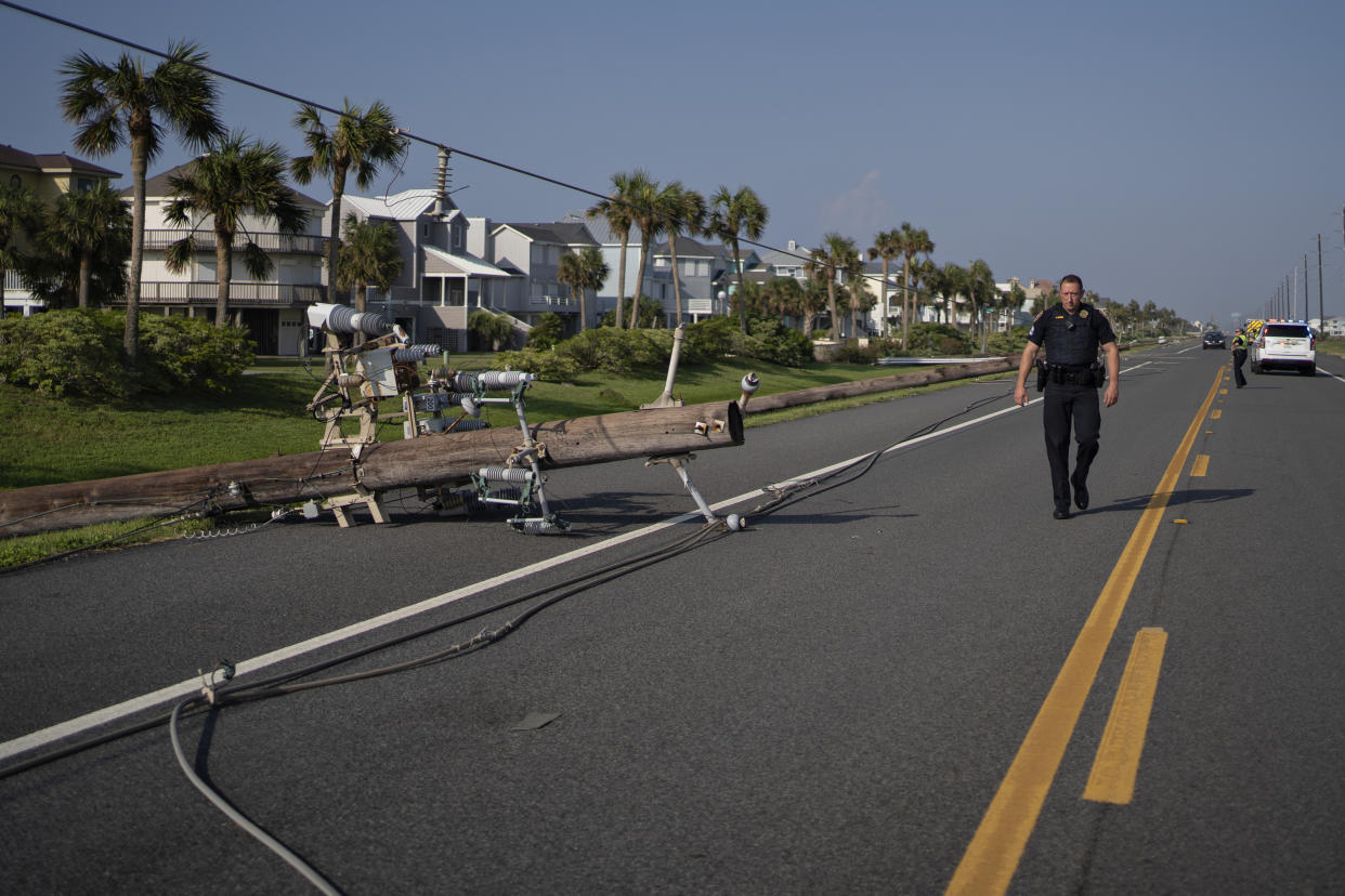 A police officer examines downed power lines in Galveston, Texas.