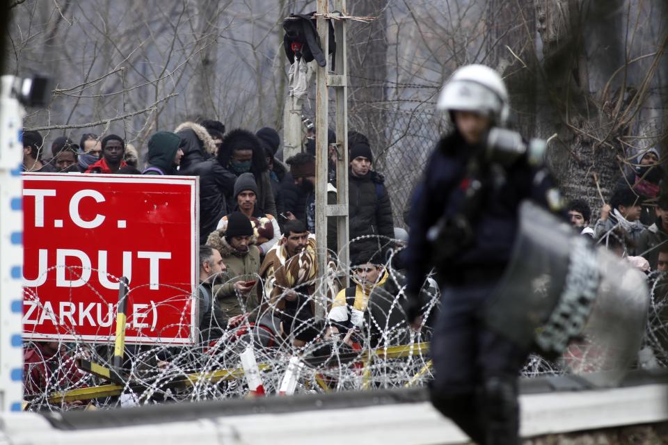 A Greek riot policeman patrols the border gate in Kastanies village as migrants trying to enter Greece from the Pazarkule border gate, Edirne, Turkey, gather at the Greek-Turkish border Saturday, Feb. 29, 2020. Turkish President Recep Tayyip Erdogan said Saturday that his country's borders with Europe were open, as thousands of refugees gathered at the frontier with Greece. (AP Photo/Giannis Papanikos)