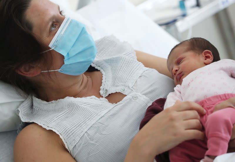 Amandine, who tested positive for the coronavirus disease (COVID-19) just before giving birth, wears a protective face mask while holding her newborn daughter Mahaut at the maternity at CHIREC Delta Hospital in Brussels