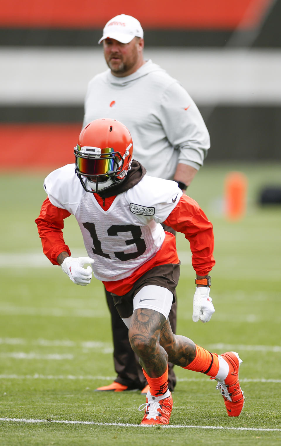Cleveland Browns wide receiver Odell Beckham Jr. (13) runs through a drill as head coach Freddie Kitchens looks on at the team's NFL football training facility in Berea, Ohio, Tuesday, June 4, 2019. (AP Photo/Ron Schwane)