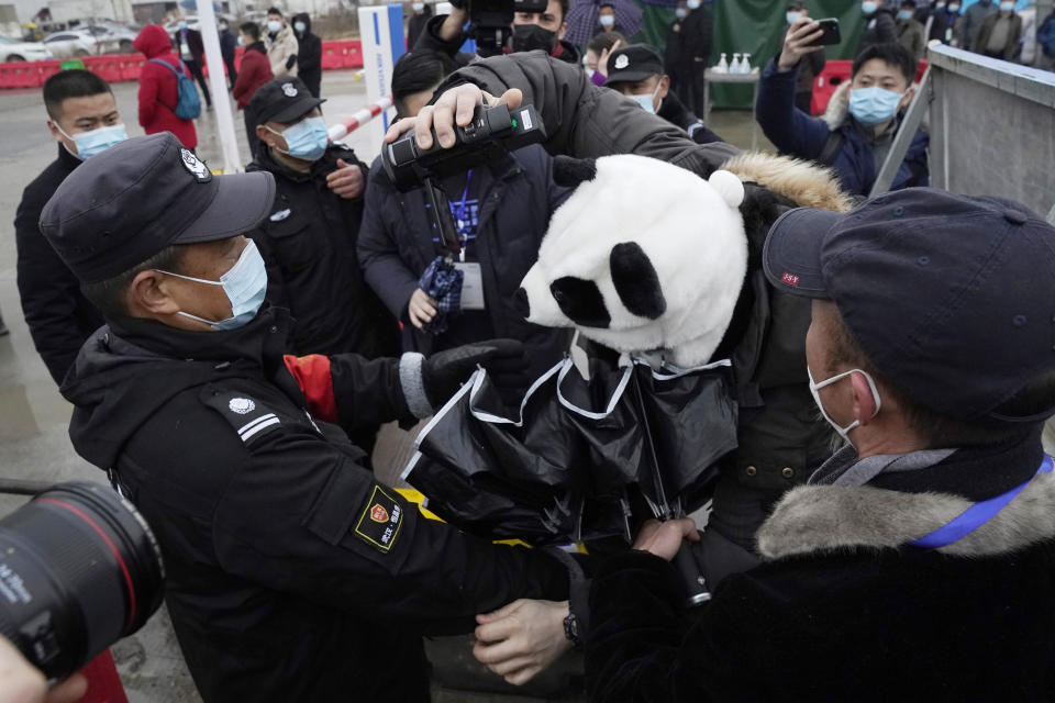 Security personnel struggle with a journalist wearing a panda design covering at the Baishazhou wholesale market during a visit by the World Health Organization team on their third day of field visit in Wuhan in central China's Hubei province on Sunday, Jan. 31, 2021. (AP Photo/Ng Han Guan)