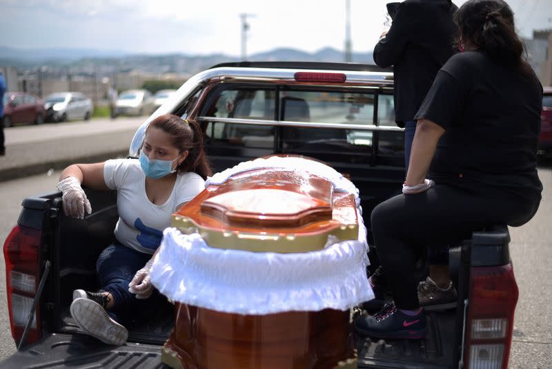 People wait next to a coffin in a pick-up truck lined up outside of a cemetery as Ecuador's government announced on Thursday it was building a "special camp" in Guayaquil for coronavirus disease (COVID-19) victims, in Guayaquil