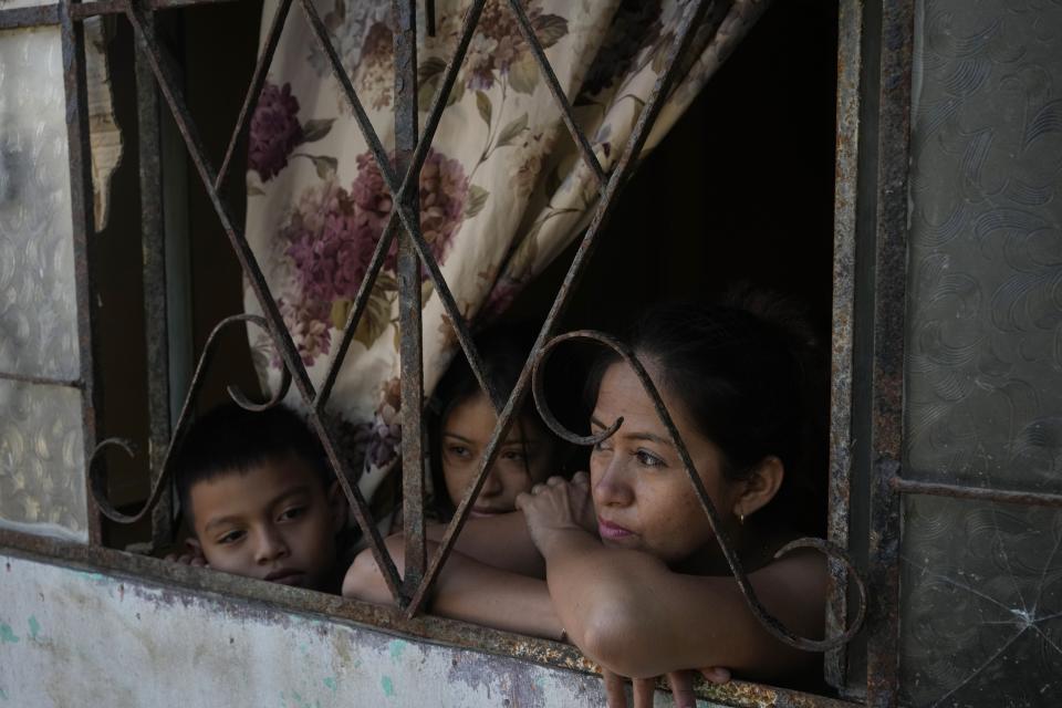 Los pacientes de dengue Ana Barco, a la derecha, su hija Angie y su hijo Enzo, miran desde su ventana en el barrio marginal Los Polvorines en Piura, Perú, el viernes 2 de junio de 2023. (AP Foto/Martín Mejía)