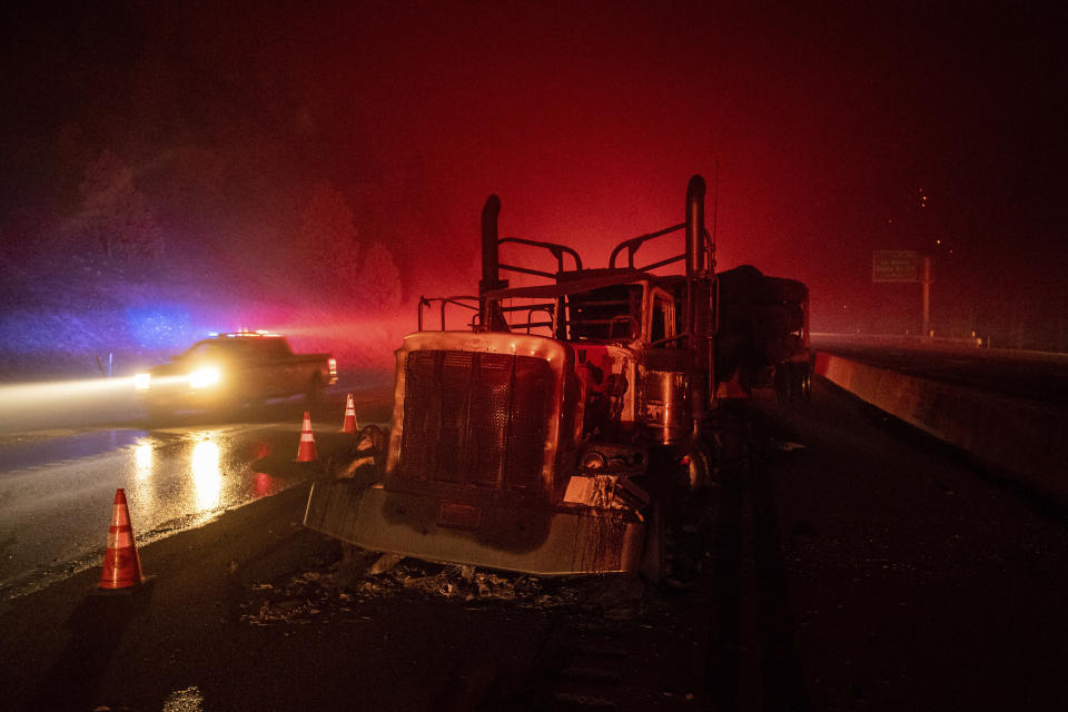 A scorched logging truck rests on Interstate 5 as the Delta Fire burns in the Shasta-Trinity National Forest, Calif., near Shasta Lake on Wednesday, Sept. 5, 2018. Parked trucks lined more than two miles of the highway as both directions remained closed to traffic. (AP Photo/Noah Berger)