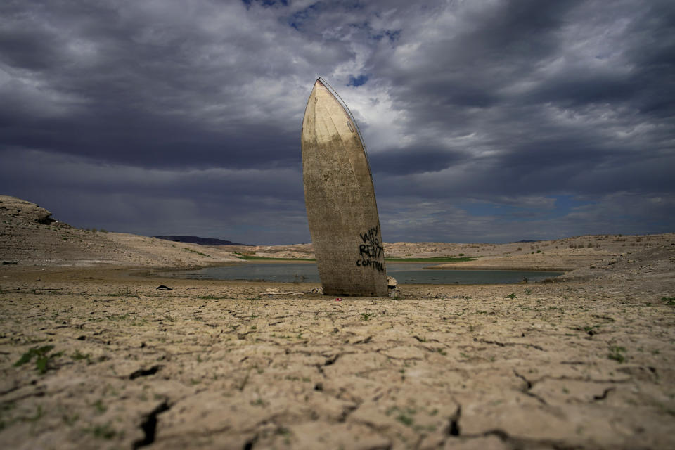 FILE - A formerly sunken boat stands upright into the air with its stern buried in the mud along the shoreline of Lake Mead at the Lake Mead National Recreation Area on June 22, 2022, near Boulder City, Nev. The U.S. Interior Department announced, Friday, Oct. 28, 2022, that it will consider revising a set of guidelines for operating two major dams on the Colorado River in the first sign of what could lead to federal action to protect the shrinking reservoirs behind them. (AP Photo/John Locher, File)