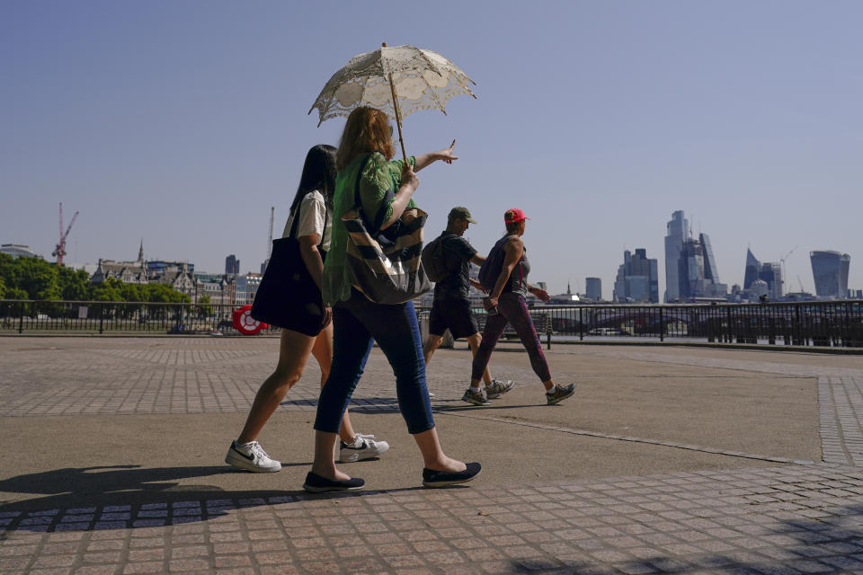 A woman holds an umbrella to shelter from the sun, as she walks on the south bank of river Thames, in London, Monday, July 18, 2022. Britain’s first-ever extreme heat warning is in effect for large parts of England as hot, dry weather that has scorched mainland Europe for the past week moves north, disrupting travel, health care and schools. (AP Photo/Alberto Pezzali)