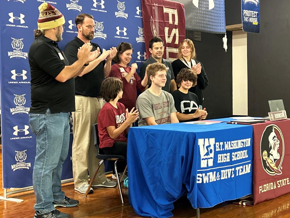 Booker T. Washington's Logan Robinson (middle, sitting) signed his letter of intent to swim at Florida State University.