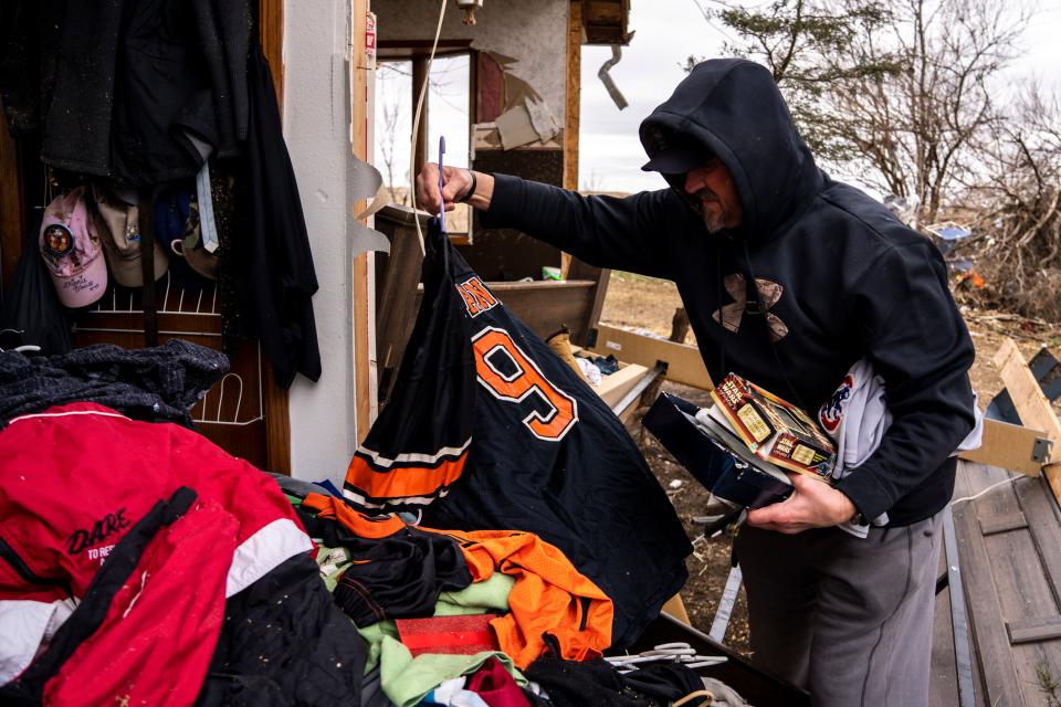Daniel Ginger sorts through clothing after the outside wall of their closet collapsed on Wednesday, April 5, 2023, the day after a tornado outside Pleasantville, Iowa.