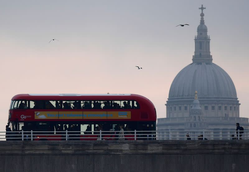 City workers cross the River Thames with St. Paul's Cathedral in the City of London financial district seen behind in London