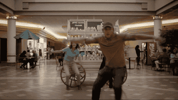 A man on a bicycle rides at full speed towards a candle wagon at a mall