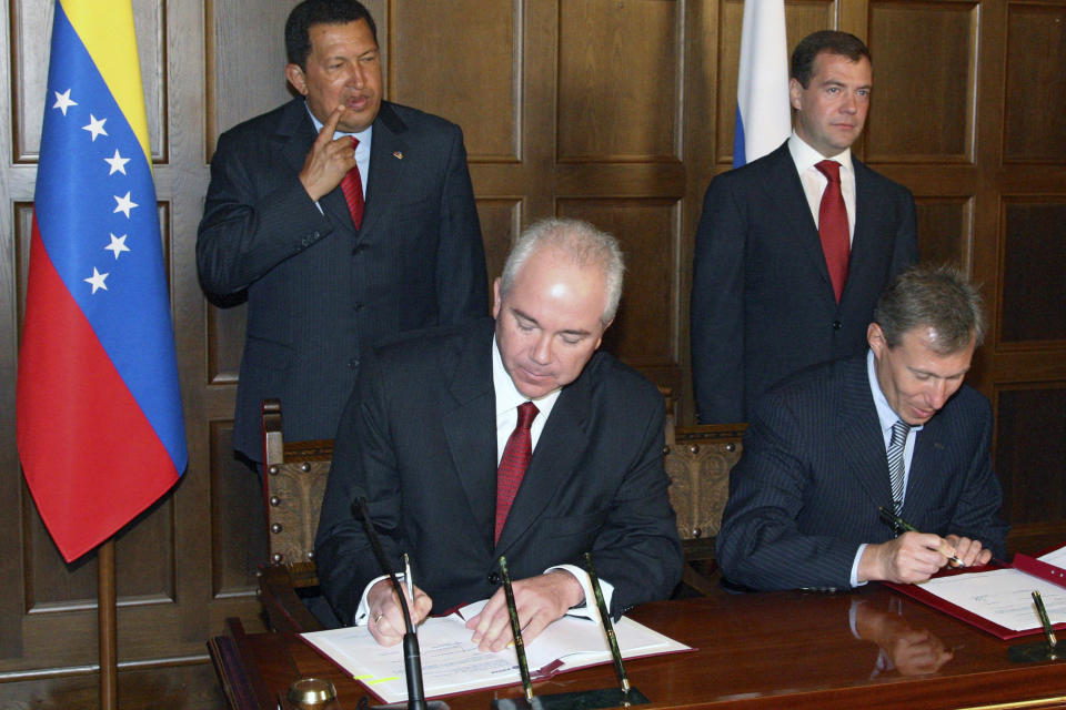 FILE - Then TNK-BP executive director German Khan, foreground left, signs papers, accompanied by Russian President Dmitry Medvedev, background right, and Venezuelan President Hugo Chavez, background left, during a ceremony in Meiendorf Castle outside Moscow, July 22, 2008. The U.S. Treasury Department on Friday, Aug. 11, 2023, imposed financial sanctions against four Russians on the board of Alfa Group, one of the country’s largest conglomerates with interests in oil, natural gas and banking. Sanctioned by Treasury are Petr Olegovich Aven, Mikhail Maratovich Fridman, German Borisovich Khan and Alexey Viktorovich Kuzmichev. (Mikhail Klimentyev/RIA-Novosti, Presidential Press Service via AP, File)