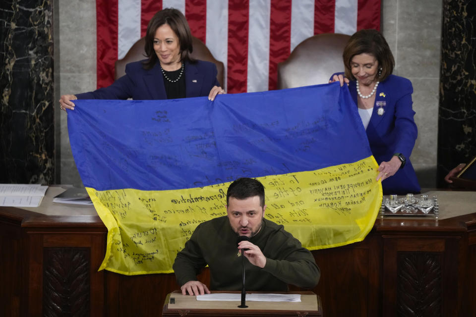 FILE - Vice President Kamala Harris and then-House Speaker Nancy Pelosi of Calif., right, react as Ukrainian President Volodymyr Zelenskyy presents lawmakers with a Ukrainian flag autographed by front-line troops in Bakhmut, in Ukraine's contested Donetsk province, as he addresses a joint meeting of Congress on Capitol Hill in Wednesday, Dec. 21, 2022. Republican reticence in the United States about Washington’s big spending to prop up Ukraine’s military has raised new uncertainties about the West’s commitment to its efforts to expel Russian invaders more than 18 months into the war. (AP Photo/Jacquelyn Martin, File)