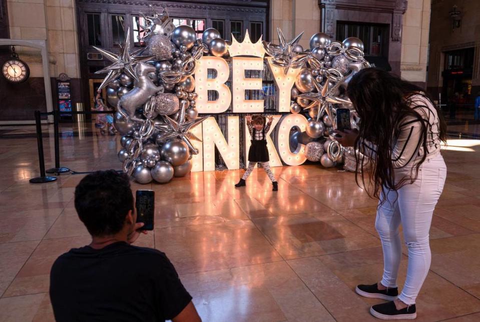 José Perera, left, and Ariana Sanchez take a photograph of Maria Sanchez in front of the Beyoncé sign on Friday at Union Station.