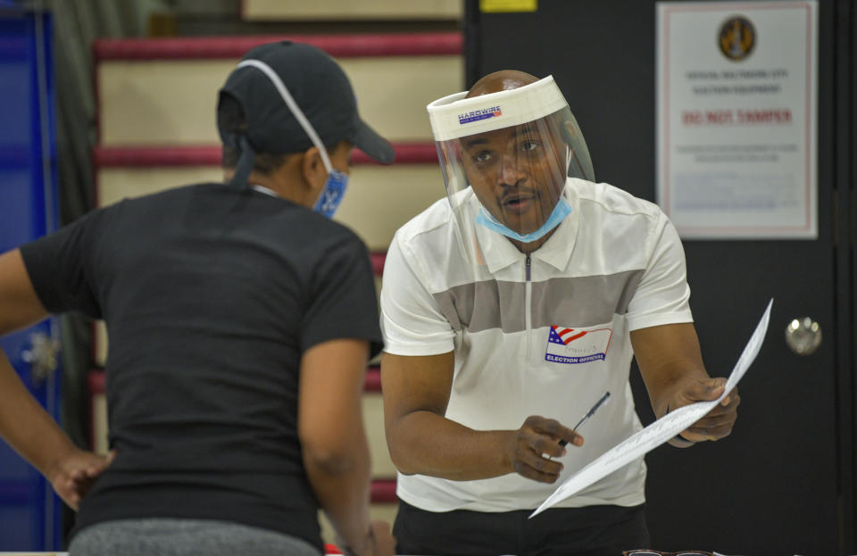 Election official Francis Vincent, right, gives instructions to a voter at Edmondson High School during the primary election in Baltimore, Tuesday, June 2, 2020. (Jerry Jackson/The Baltimore Sun via AP)