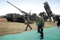 Japan's Prime Minister Fumio Kishida, center right, walks past a Japan Ground Self-Defense Force (JGSDF) Type 19 155-mm wheeled self-propelled howitzer, rear left, and a Type 12 surface-to-ship missile, rear right, as he inspects weapons during a review at the JGSDF Camp Asaka in Tokyo, Japan, Saturday, Nov. 27, 2021. (Kiyoshi Ota/Pool Photo via AP)