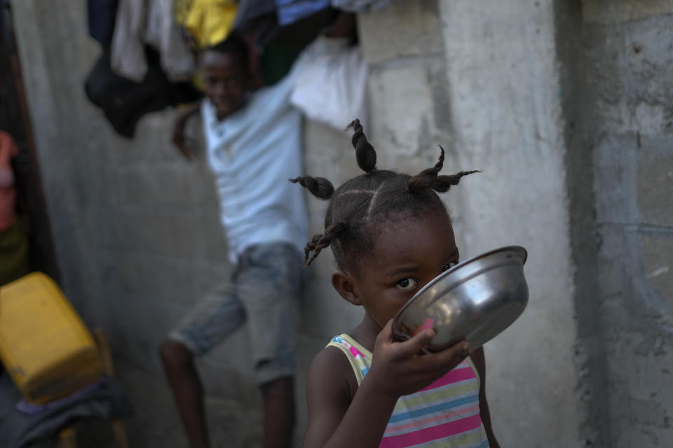 FILE - A girl drinks coffee from a dish at a shelter for families displaced by gang violence, in Port-au-Prince, Haiti, Nov. 13, 2021. World Vision International, a California-based organization that helps children in Haiti, told The Associated Press that it has relocated at least 11 of 320 employees as a result of the violence and is taking undisclosed security measures for other staff. (AP Photo/Matias Delacroix, File)