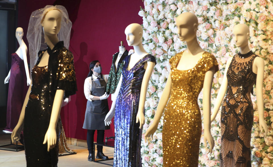 A gallery assistant handles the oak leaf 'Glamouflage' jacket made for Mick Jagger, amongst other items on display at Christie's, from the archive of fashion designer L'Wren Scott before it is offered at auction, in London, Thursday June 10, 2021. (Jonathan Brady/PA via AP)