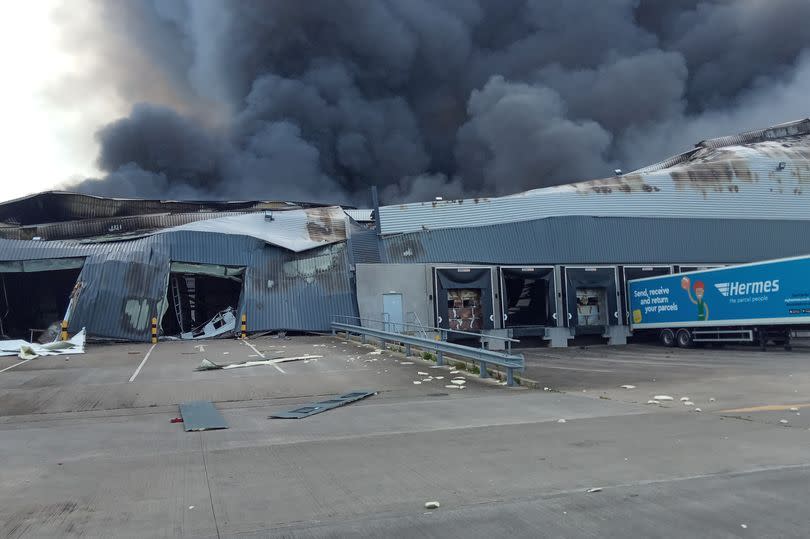 The scene of the aftermath of the fire in Cannock, where the gutted shell of an industrial building remains. Thick smoke can be seen billowing into the sky. -Credit:Richard Pursehouse