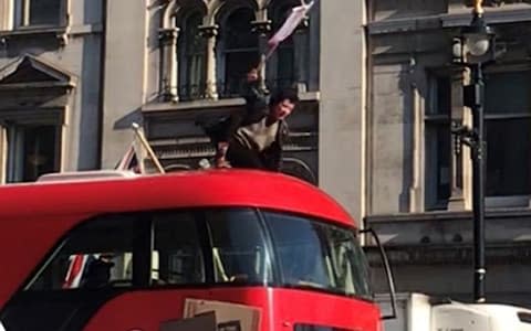 A person on top of a double decker bus as students from the Youth Strike 4 Climate take part in a climate change protest in Parliament Square, Westminster, London - Credit: Verity Bowman/PA