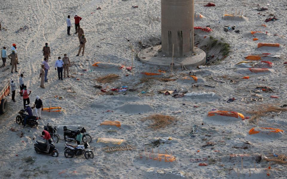 Policemen inspect bodies buried in shallow graves on the banks of Ganges river in Prayagraj, India - Rajesh Kumar Singh /AP