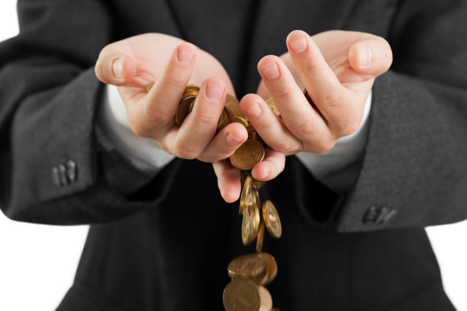 A man holding coins spilling through his hands.