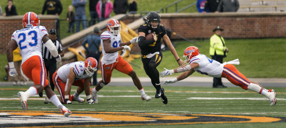 Missouri quarterback Drew Lock, center, runs between Florida defenders during the first half of an NCAA college football game Saturday, Nov. 4, 2017, in Columbia, Mo. (AP Photo/L.G. Patterson)