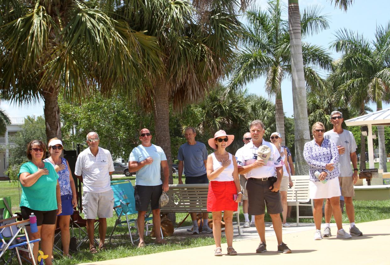 Rising for the singing of "The Star Spangled Banner," this group in Gilchrist Park were among those that came out for the 30th Annual Freedom Swim, choosing to watch from Gilchrist Park in Punta Gorda.