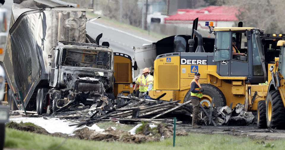 Workers clear debris from the eastbound lanes of Interstate 70 on Friday, April 26, 2019, in Lakewood, Colo., after a deadly pileup involving semi-truck hauling lumber on Thursday. Lakewood police spokesman John Romero described it as a chain reaction of crashes and explosions from ruptured gas tanks. "It was crash, crash, crash and explosion, explosion, explosion," he said. (AP Photo/David Zalubowski)