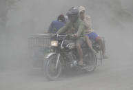 In this Jan. 13, 2020, photo, a family rides their motorcycle through clouds of ash as they evacuate to safer grounds as Taal volcano in Tagaytay, Cavite province, southern Philippines. Red-hot lava is gushing from the volcano after a sudden eruption of ash and steam that forced residents to flee and shut down Manila’s airport, offices and schools. (AP Photo/Aaron Favila)