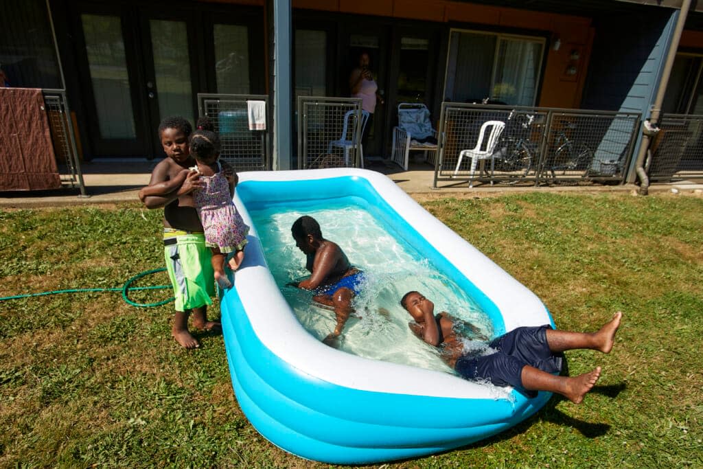 Jalen Askari, 7, right, plugs his nose as he falls into the pool he is playing in with his siblings, from left, Amari, 5, Bella, 2, and DJ, 10, in Portland, Ore., Tuesday, July 26, 2022. (AP Photo/Craig Mitchelldyer)