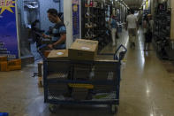 A delivery worker pushes a cart loaded with goods as women shop for shoes at Ritan International Trade Center in Beijing on Wednesday, May 15, 2024. Data released on Friday, May 17 showed housing prices in China slumped for the first four months of the year, although factory output rose nearly 7%, as the country prepares to announce fresh measures to reinvigorate its ailing property industry. (AP Photo/Andy Wong)