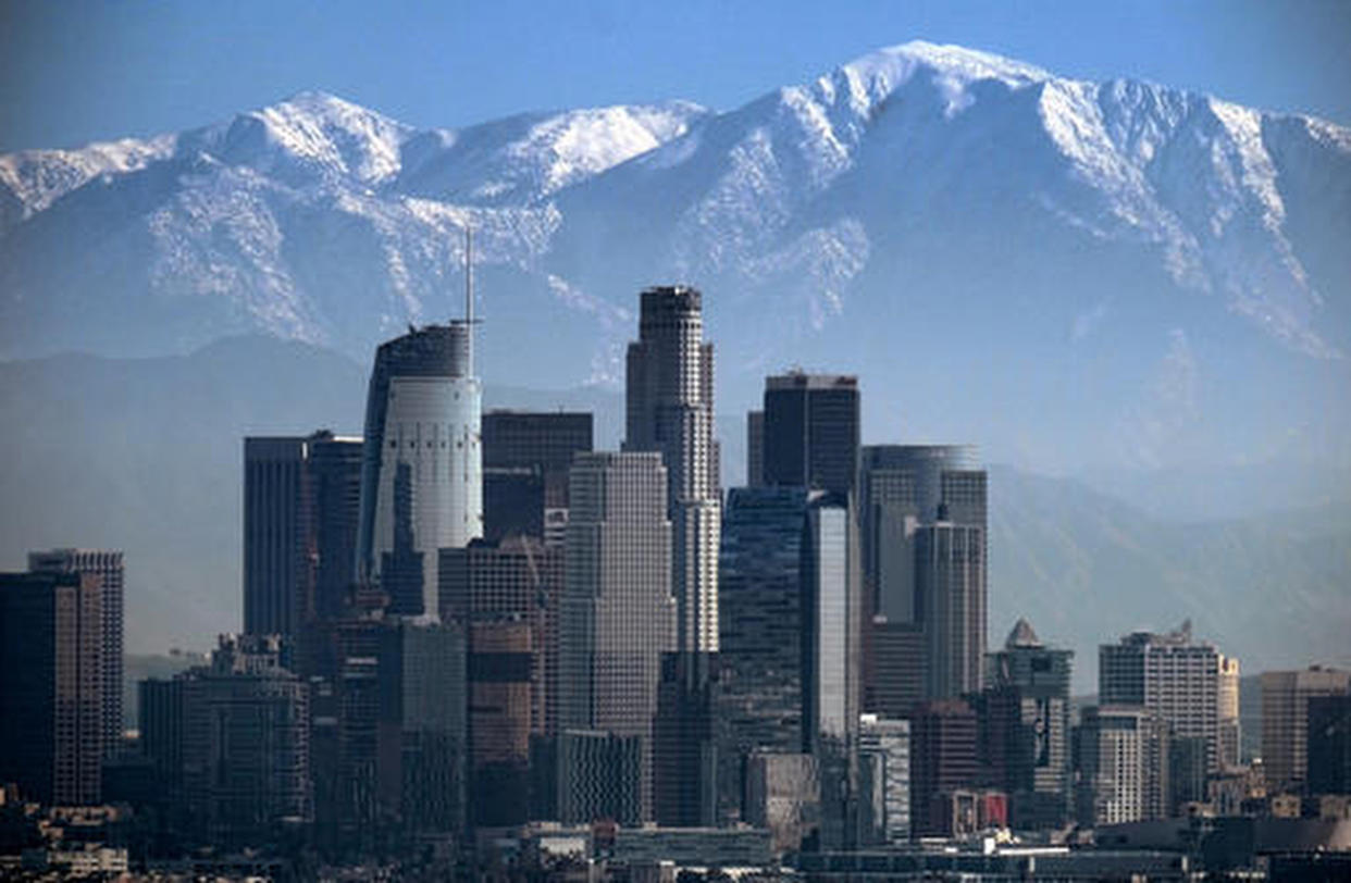 FILE - A snow-covered Mount Baldy, the highest peak among the San Gabriel Mountains, looms behind downtown Los Angeles, on Jan. 25, 2017. Rescue personnel in California say they have launched a search for a second hiker on the same snow-covered mountain where actor Julian Sands is missing. The San Bernardino Sheriff's Department says its search and rescue team received a request Sunday, Jan. 22, 2023, to search for 75-year-old Jin Chung, of Los Angeles, on Mt. Baldy. (AP Photo/Richard Vogel, File)