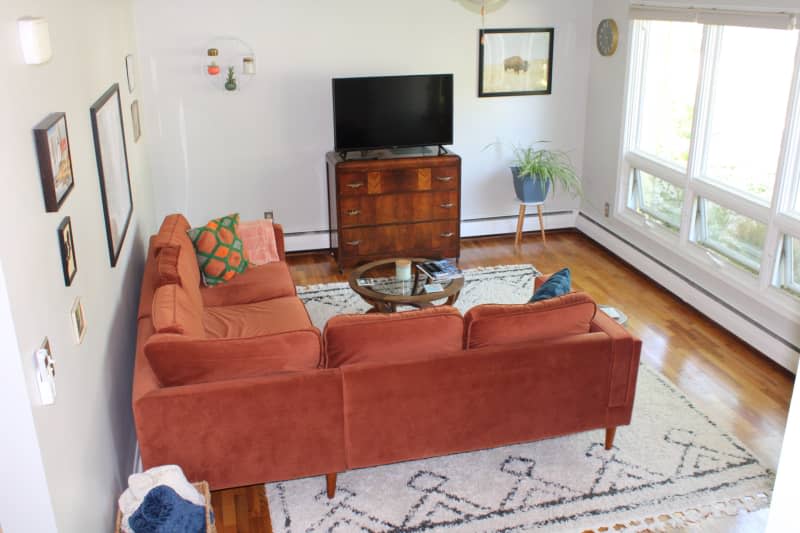 Orange L-shaped fabric couch on a large white and black patterned area rug.