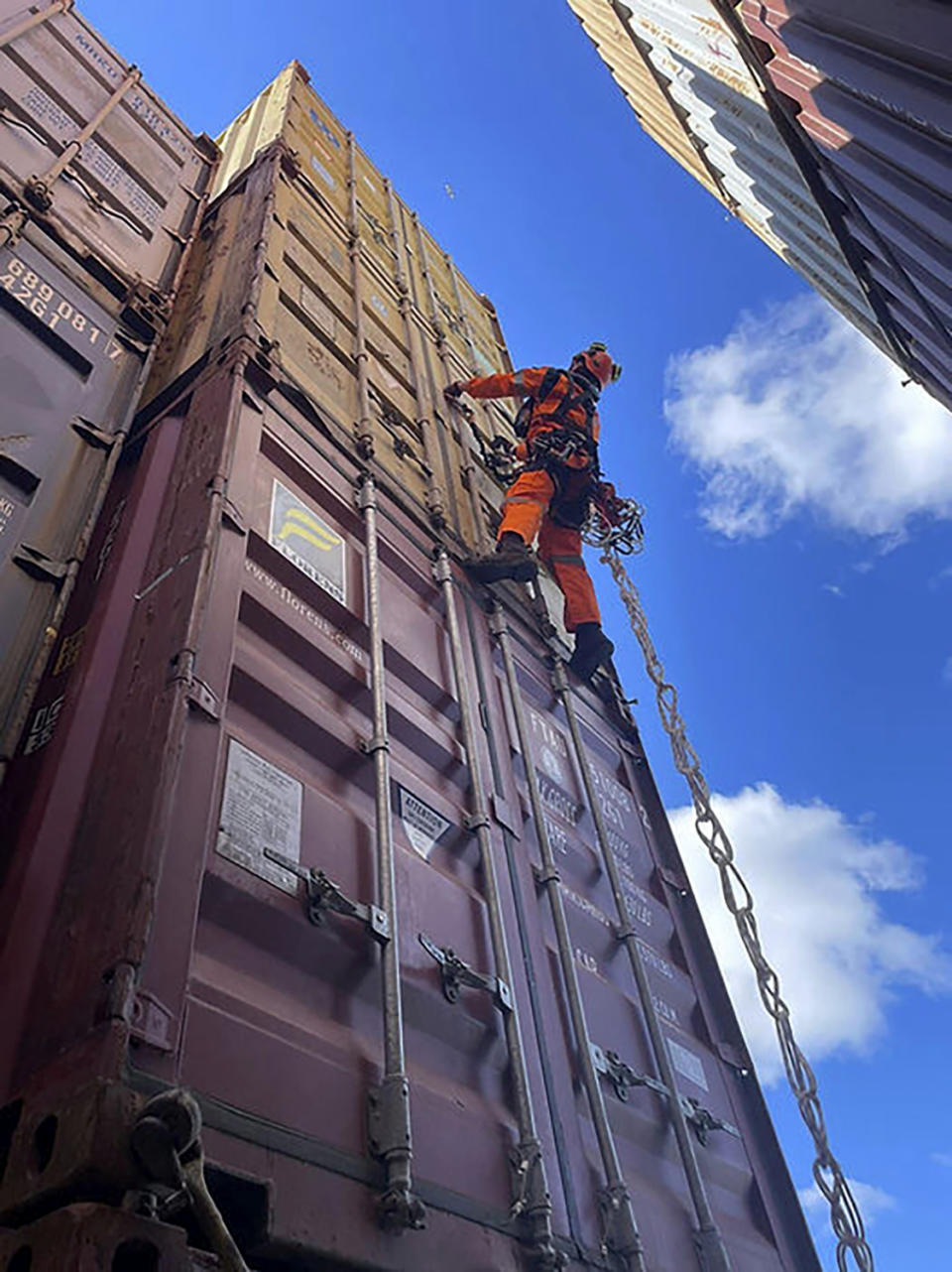 In this photo provided by the Key Bridge Response 2024 Unified Command, a specialized salvage climber scales a container to survey the damage to containers onboard the cargo ship Dali at the site of the Francis Scott Key Bridge, Saturday, April 6, 2024, in Baltimore. Salvage crews on Sunday began removing containers from the deck of the cargo ship that crashed into and collapsed the bridge, an important step toward the full reopening of one of the nation’s main shipping lanes. (Key Bridge Response 2024 Unified Command via AP)