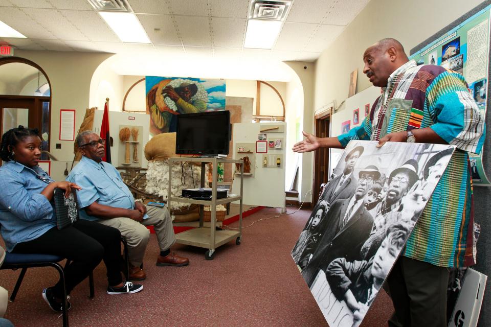 Clayborn Benson holds a photo of Lloyd Barbee, civil rights attorney, as he talks about the Milwaukee fair housing marches to visitors from Atlanta on July 28, 2017, at the Wisconsin Black Historical Society and Museum. Benson knows education is critical to connecting people with their roots. LaDonna Williams and her father, Don Williams from Atlanta, listen to Benson.