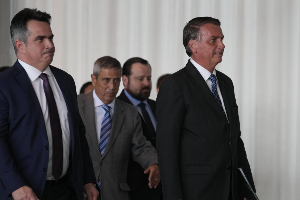 Brazilian President Jair Bolsonaro, right, arrives to speak from his official residence of Alvorada Palace in Brasilia, Brazil, Tuesday, Nov. 1, 2022, the leader's first public comments since losing the Oct. 30 presidential runoff. Behind are Ciro Nogueira, Chief of Staff of the Presidency of Brazil, far left, and Gen. Walter Braga Netto, his running-mate for reelection, second from left. (AP Photo/Eraldo Peres)
