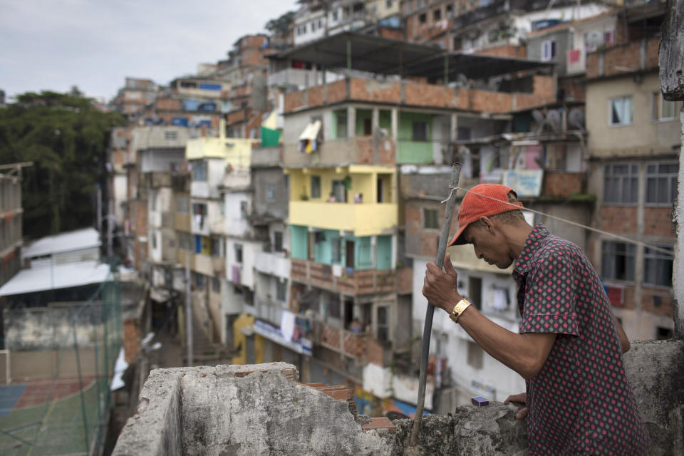 El residente M.C. Bum mira hacia abajo desde el balcón donde los residentes dicen que Douglas Rafael da Silva Pereira cayó hasta el lugar donde hallaron su cuerpo en la favela Pavao Pavaozinho, en Río de Janeiro, Brasil, el miércoles 23 de abril de 2014. (AP Foto/Felipe Dana)