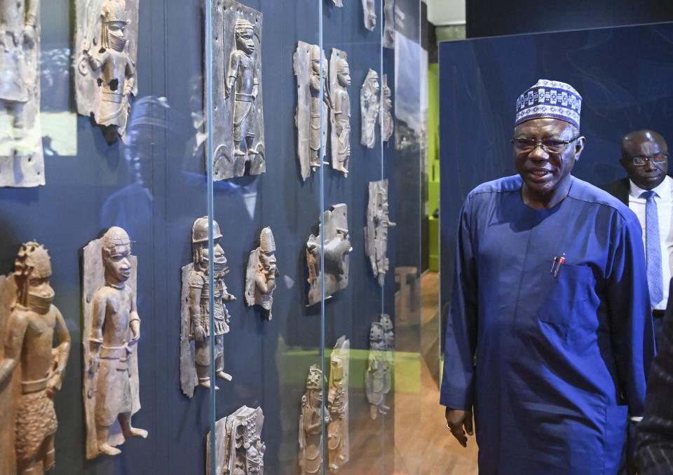 Abba Tijani, director general of the National Museums and Monuments Authority of Nigeria, looks at Benin Bronzes at the Linden Museum in Stuttgart, Germany, Wednesday June 29, 2022 . The ethnological museum houses 78 objects, including 64 bronzes,from the former royal house of Benin, whose core area is located in what is now southwestern Nigeria. Germany is set to sign an agreement in Nigeria that paves the way for the return of important sculptures known as the Benin Bronzes that were taken from Africa in the late 19th century. (Bernd Weissbrod/dpa via AP)